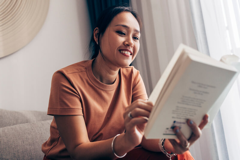 Asian woman enjoying her free time, reading a book.